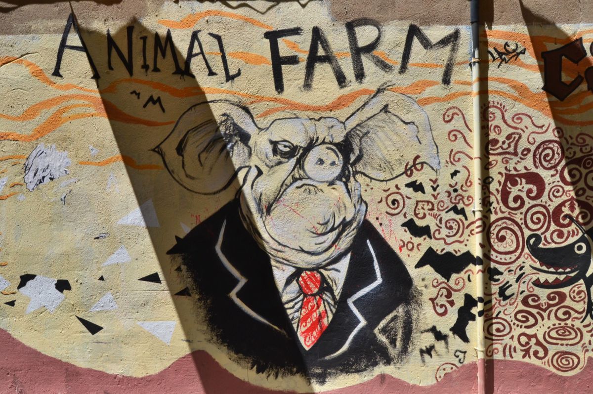 Street mural of a pig in a business suit, painted below the words Animal Farm